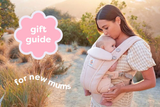 Outdoor setting showing woman kissing her baby's head as she wears her in an Ergobaby Omni Breeze carrier, a practical baby shower gift for mom.