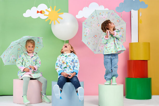 three children happily wearing Penny Scallan Rain Jackets in a bright room showing their fit and patterns