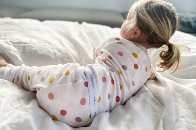Back view of toddler on a bed wearing a polka dot Snugglebum girls' pyjama set showing the soft fabric and waistband detail.