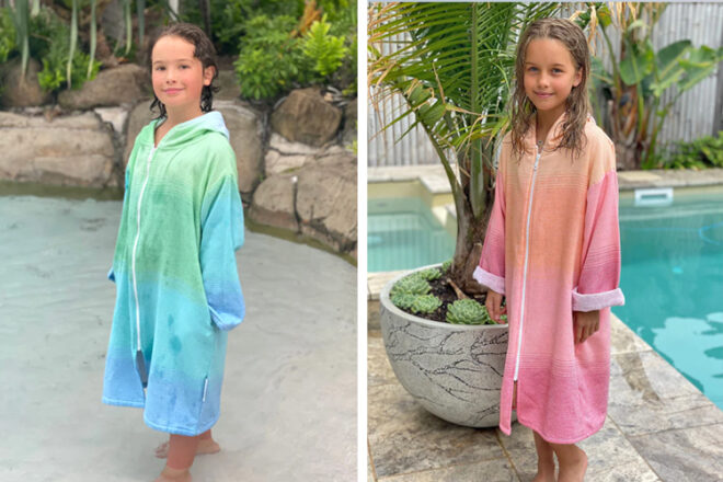 Front view of two children wearing Back Beach Co hooded poncho towels, showing use of towel in pool setting, zipped up for full coverage and showcasing two different colourways, blue/green and orange/pink.