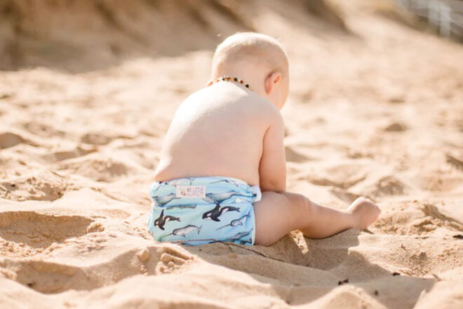 Back view of baby wearing My Little Gumnut water-resistant nappy, showing use on the sand, as well as sea creature print. 