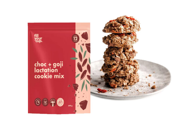 Fill Your Cup Lactation Cookies Mix showcasing a close up of five milk-making cookies of the same variety are stacked on a plate with scattered crumbs so you can clearly see the texture, detail and ingredients.of the choc + goji lactation cookie mix in a resealable packaging.