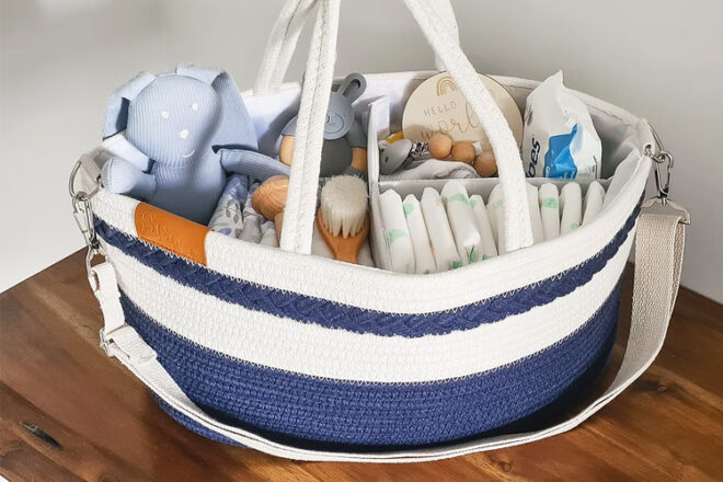 View looking down on Spring Farm Babies nursery organiser showing ample capacity with compartments fully stocked, as well as showcasing colour and texture of basket, shoulder strap and carry handles.