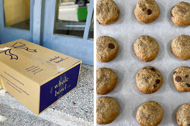 The Whole Bowl Co Lactation Cookies displayed in a delivery box, showcasing that these cookies can be conveniently delivered right to your door. Twelve freshly baked choc chip nursing cookies are arranged on top of a sheet of baking paper, highlighting their soft texture and enticing aroma.