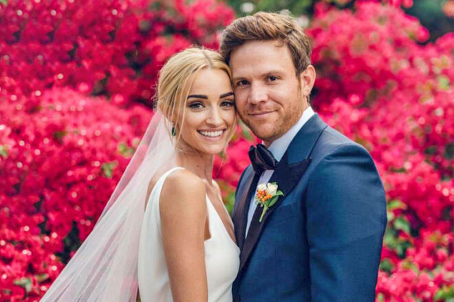 Brianne Howey and Matt Ziering showing a wedding photo surrounded by pink flowers