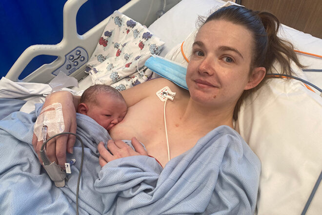Laura O breastfeeding her newborn baby in a hospital bed