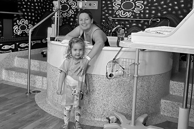 Mindy in the water bath in the hospital with daughter watching her give birth