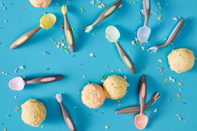 B.Box baby cutlery laying between sprinkles and balls of ice cream showing colours and size comparison