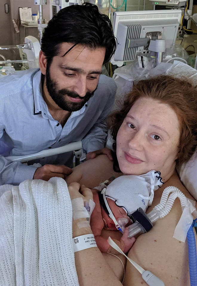 A mother and father with their baby after giving birth in hospital.