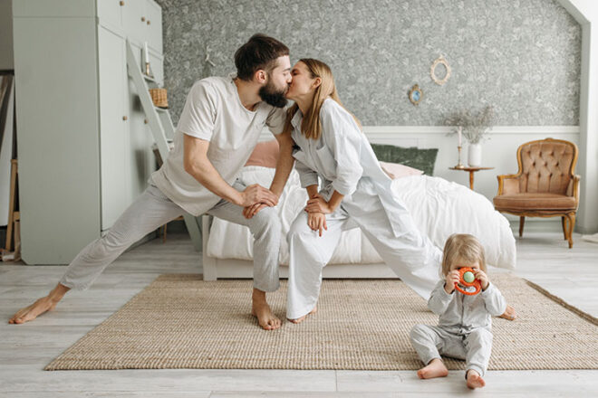 Happy couple kissing doing yoga with toddler