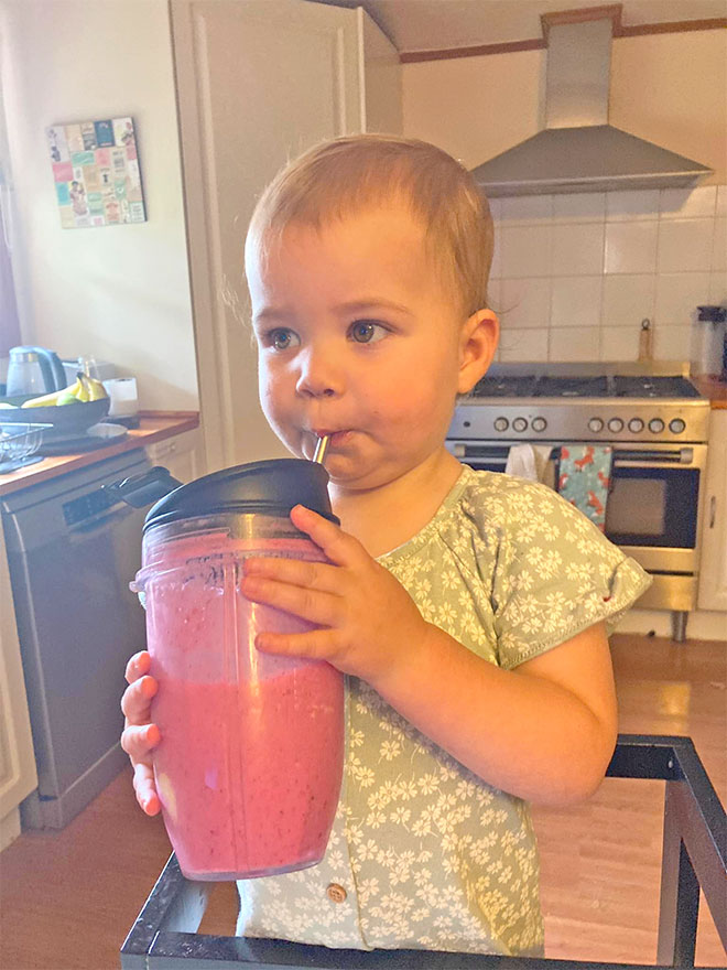 Toddler drinking Optivance Toddler Smoothie from a straw sippy cup.