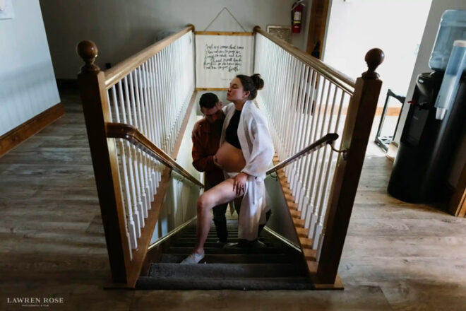 Pregnant mother being helped up the stairs by partner