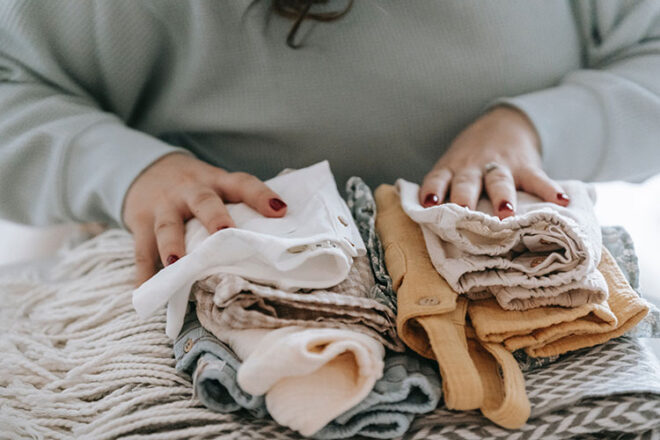 Mother folding a pile of baby clothes
