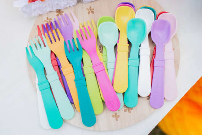 Replay baby cutlery forks and spoons laying on a table showing range of colours and design