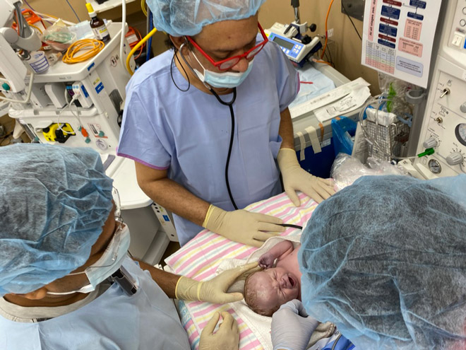 Doctors examine a newborn baby