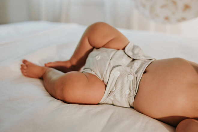 Baby lying on bed wearing Bare & Boho Cloth Nappy