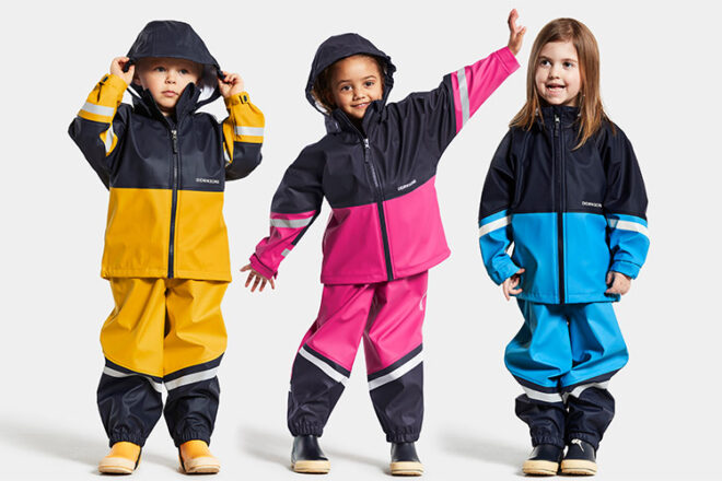 Three children side by side wearing Didriksons toddler raincoats showing the different colours and styles available.