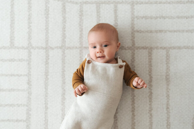 Baby lying on their back on a Mikro rectangle padded baby play mat