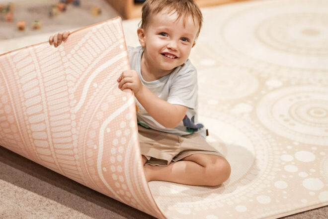 Child holding the Oaker Design play mat up in the corner showing the reverse design
