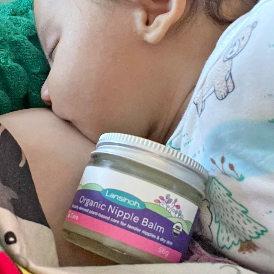 Mum breastfeeding baby showing the Lansinoh Organic Nipple Balm