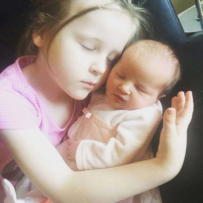 A toddler cuddles her newborn sister