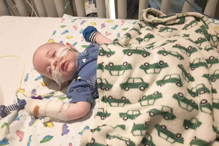 A baby with RSV asleep in a hospital bed.