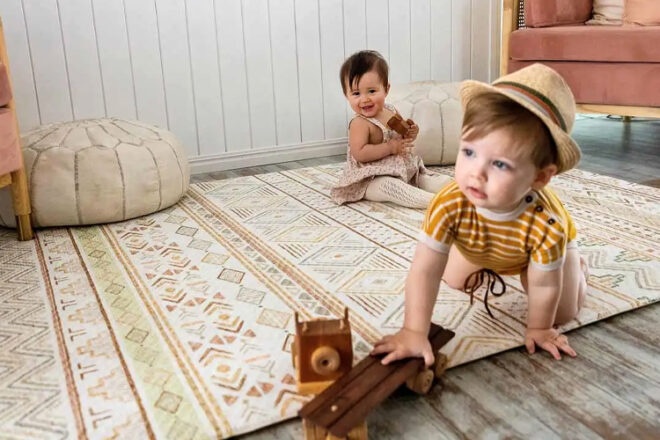 Two children playing on a play mat by Rockabye River