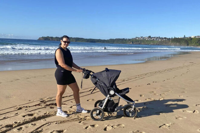 Shae walking along the beach with her Bumbleride Indie pram