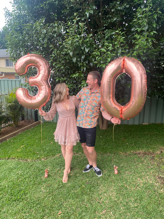 Tegan and Andrew holding 30th Birthday balloons