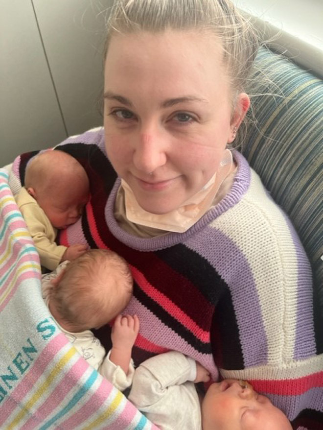 Caitlin holds her three babies in hospital