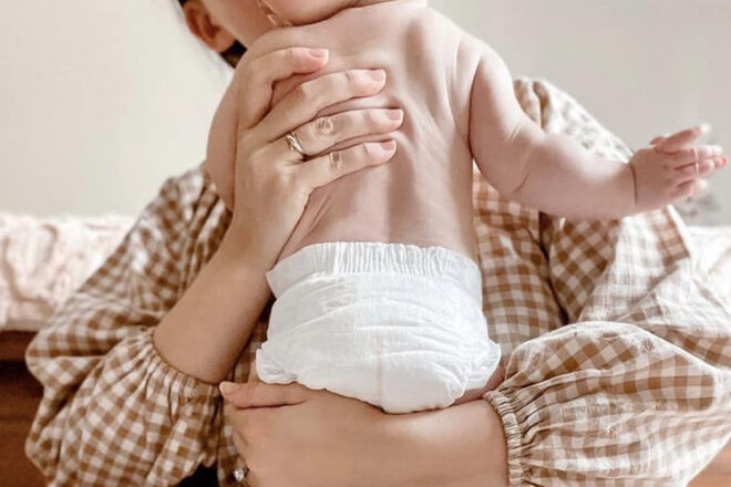 Baby being held by mother wearing Cuddlies Co nappies