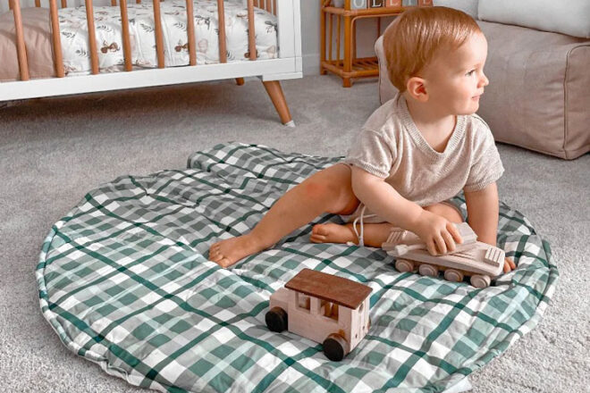 A child sitting and playing on a Snuggly Jacks play mat 