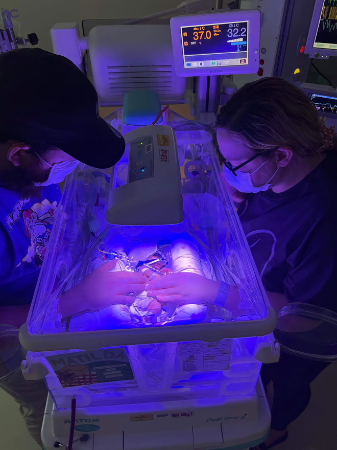 A newborn baby is in a crib under UV lights