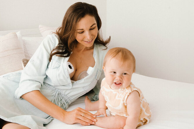 mother sitting with her child wearing night owl breast pumps in her dress showing discrete style