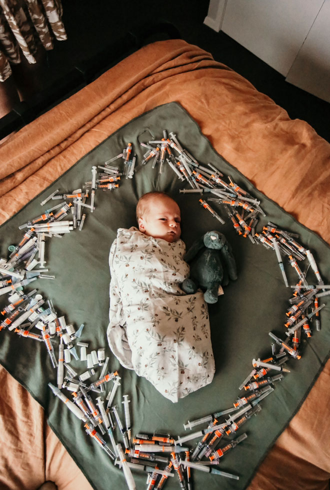 baby wrapped up surrounded by ivf needles
