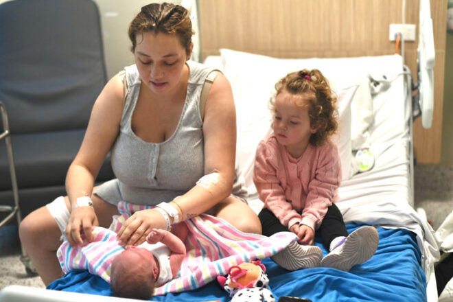 Mother and daughter sitting on hospital changing a newborn baby