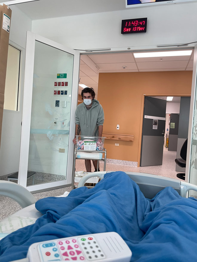 husband on the maternity ward pushing a cart to wife in bed