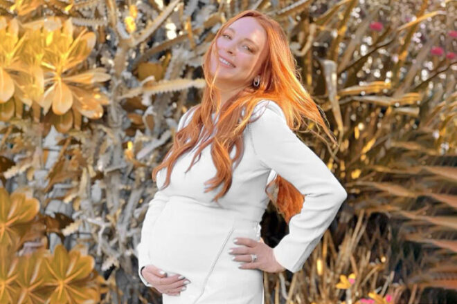 Lindsay Lohan in a white dress holding her baby bump