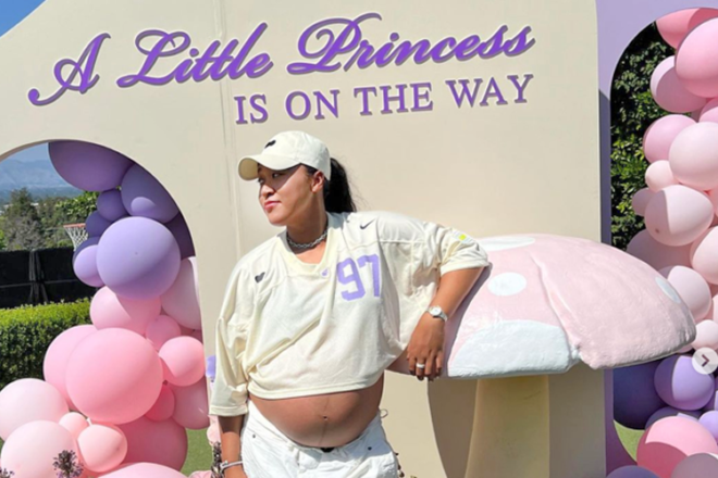 Naomi Osaka at her baby shower standing under a sign that says' A little princess is in the way,