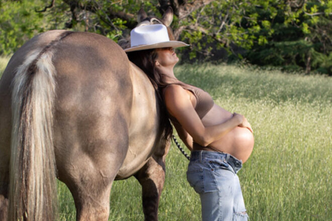 Nikki Reed leaning on a horse showing her pregnant belly