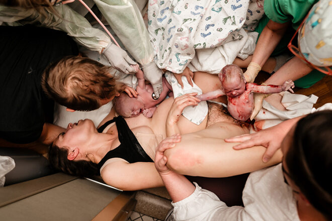 A woman in active birth with her first baby held against her chest