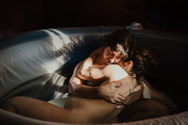 Two people embracing in a paddle pool during active labour