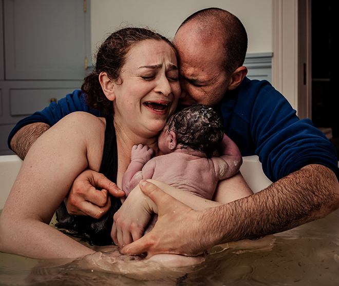 Mother and Father cradling their newborn baby after birth