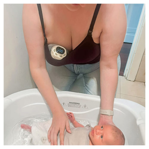 Mum using the Welcare Nurture Wearable Electric Breast Pump while bathing baby