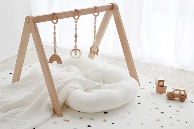 Wooden activity baby play gym sitting over a baby lounger