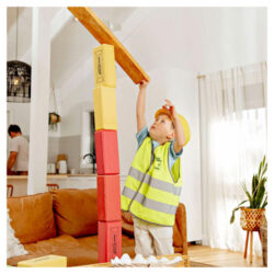 Child wearing a builder's costume playing with KICKBrick Kick Bricks