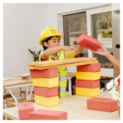 Child wearing a builder's costume playing with KICKBrick Kick Bricks