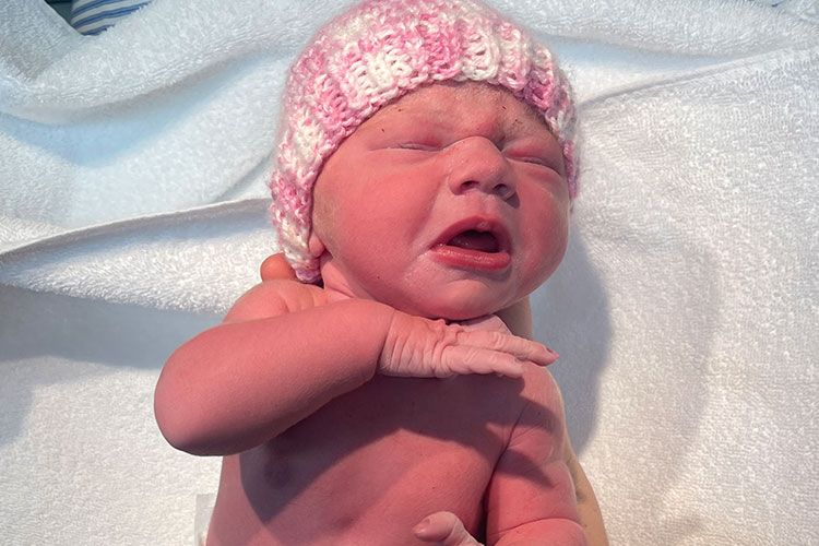 A newborn baby wears a pink beanie