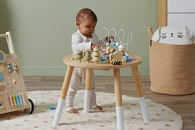Mocka activity table showing a toddler standing up to use the play equipment on top in soft and soothing colour schemes
