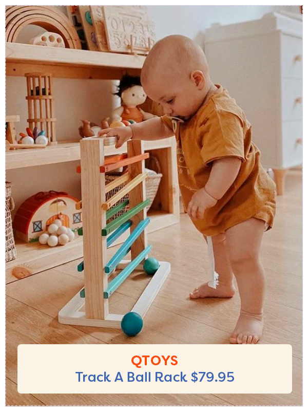Baby standing next to the QToys Track a Ball toy